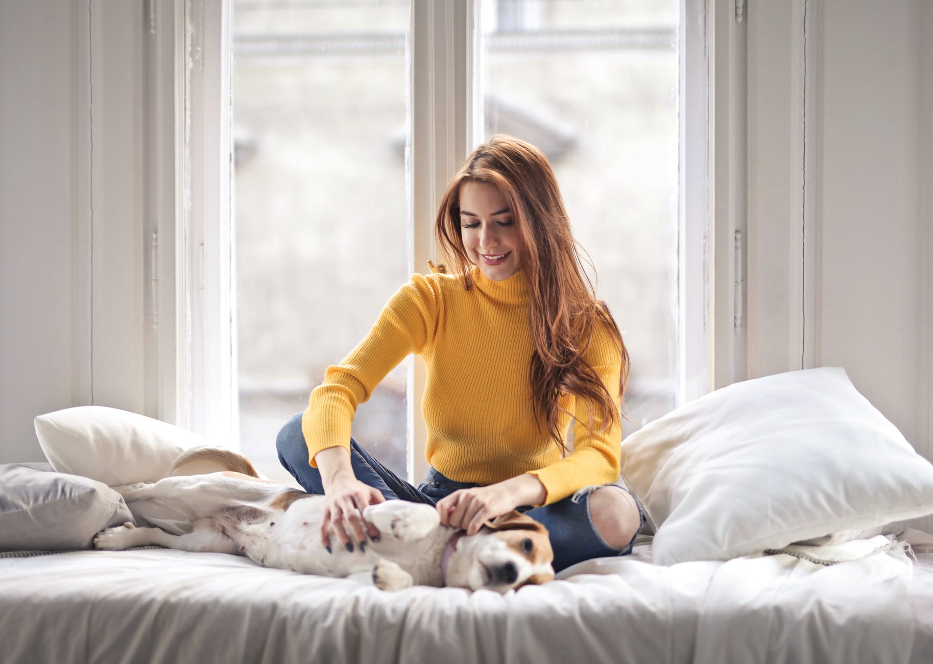 Woman sat on the bed with her pet dog