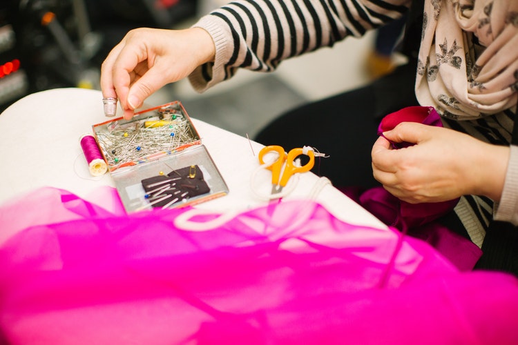 Woman making something from pink fabric