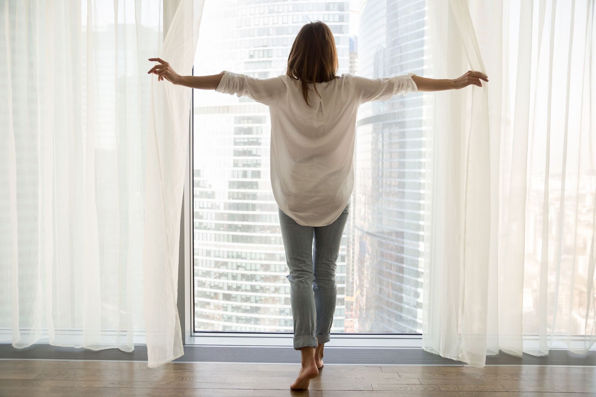 Woman opening curtains to let in natural light