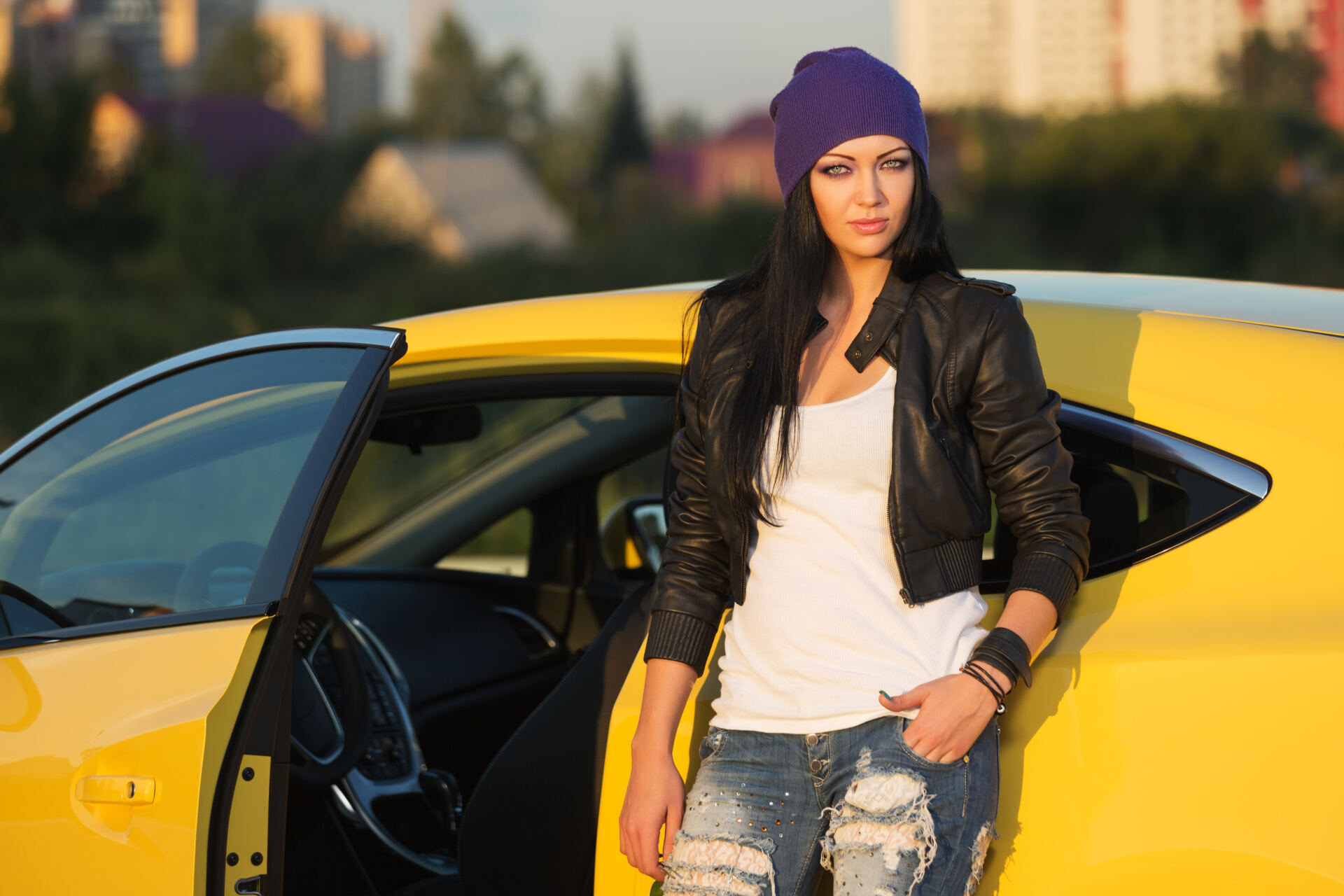 Fashionable young woman leaning on a yellow car and wearing ripped jeans Fashionable young woman leaning on a yellow car and wearing ripped jeans